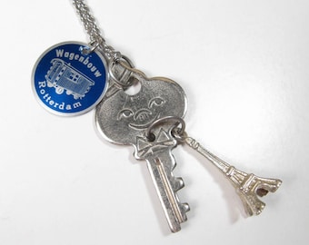 Handgemaakte charmeclusterketting vintage American Tourister Key reclamelabel en Eiffeltorenbedel