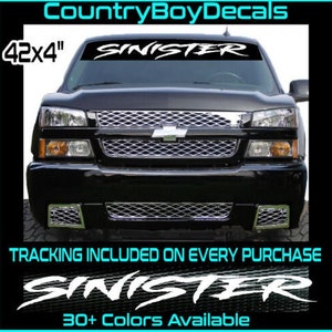 May include: A black truck with a white windshield banner that reads "SINISTER" in a stylized font. The banner is 42 inches by 4 inches. The truck has a chrome grille and headlights. The image also includes the text "TRACKING INCLUDED ON EVERY PURCHASE" and "30+ Colors Available".