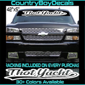 May include: A white vinyl decal with the text "Thot Yacht" in a cursive font. The decal is 42 inches wide and 5 inches tall. The decal is shown on the windshield of a black pickup truck. The text "RACKING INCLUDED ON EVERY PURCHASE" and "30+ Colors Available" are also visible in the image.