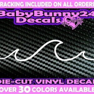 Könnte beinhalten: Weißer Vinyl-Aufkleber mit einer Welle auf einem schwarzen Carbonfaser-Hintergrund. Der Aufkleber ist gestanzt und in über 30 Farben erhältlich.  "BabyBunny24 Decals" ist in Pink oben im Bild gedruckt.