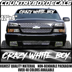 May include: A black truck with a white windshield banner that reads "CRAZY WHITE BOY" in a stylized font. The banner is 42 inches by 4 inches. The truck is in front of a white background with the text "HIGHEST QUALITY MATERIAL NON-BENDABLE PACKAGING OVER 40 COLORS AVAILABLE" at the bottom.