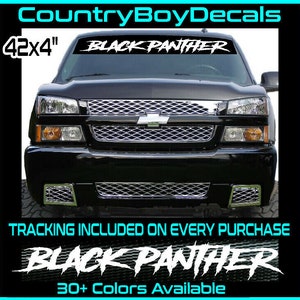 May include: Black Panther windshield decal, 42x4 inches, in white, displayed on a black truck. The decal features the text "BLACK PANTHER" in a bold, stylized font. The image also includes the text "30+ Colors Available".