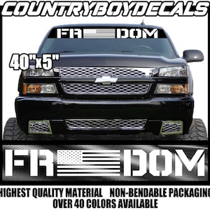 May include: A black truck with a white "FREEDOM" decal on the windshield. The decal features an American flag with white stars and red and white stripes. The decal is 40 inches by 5 inches.
