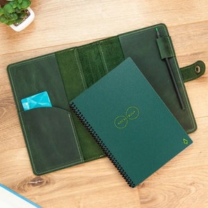 Peut inclure: Une couverture de carnet en cuir vert avec un carnet à spirales à l'intérieur. Le carnet a une couverture verte avec le texte "NOTEBOOK" dans un cercle.