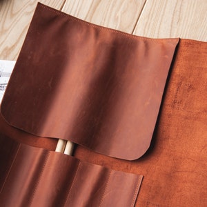 May include: A brown leather roll with multiple slots for holding drumsticks. The roll is open and two drumsticks are visible inside.