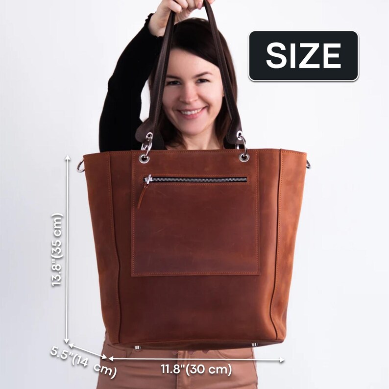 K&ouml;nnte beinhalten: Eine braune Ledertasche mit einem Rei&szlig;verschlussfach auf der Vorderseite. Die Tasche ist 35 cm hoch, 30 cm breit und 14 cm tief.