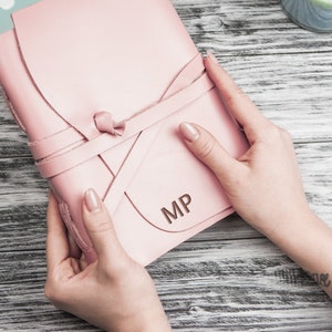 May include: A pink leather journal with a leather tie closure and the initials "MP" embossed on the front.