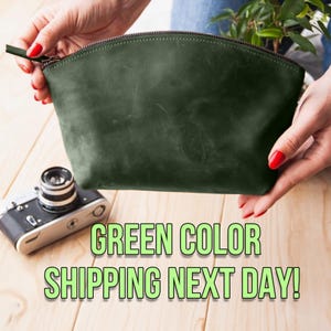 May include: A dark green leather zippered pouch or cosmetic bag. The bag is held in a person's hands. The text "GREEN COLOR SHIPPING NEXT DAY!" is below the bag.