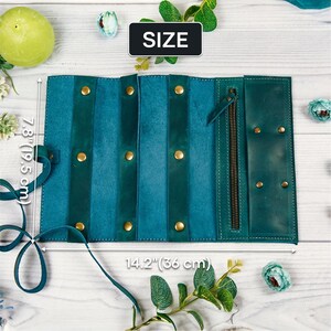May include: Teal leather jewelry roll with a zipper closure and gold-toned hardware. The roll measures 7.8 inches by 14.2 inches. SIZE is written on a white label.