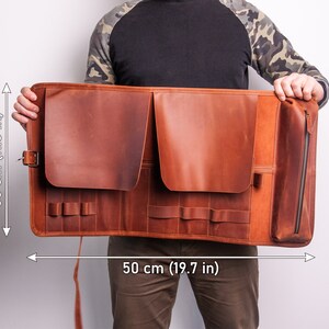 Peut inclure: Un porte-outils enroulable en cuir marron avec plusieurs poches et une poche zipp&eacute;e. Il mesure 50 cm de large et 30 cm de haut.