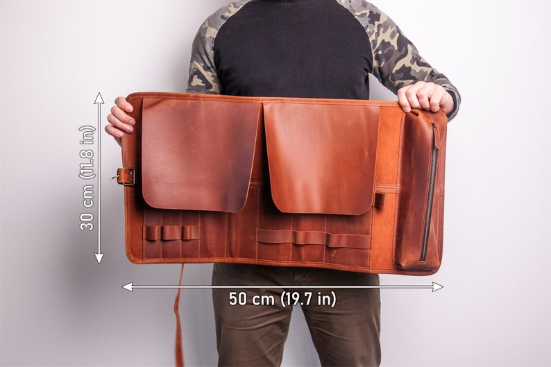 Peut inclure: Un porte-outils enroulable en cuir marron avec plusieurs poches et une poche zipp&eacute;e. Il mesure 50 cm de large et 30 cm de haut.