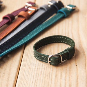 May include: A set of six leather watch bands in various colors, including burgundy, brown, gray, blue, and green. The bands are stitched with white thread and have silver buckles.