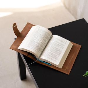 May include: A brown leather book cover with a bookmark. The book is open and the pages are white.