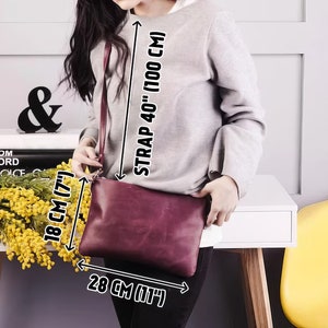 Peut inclure: Un sac &agrave; bandouli&egrave;re en cuir bordeaux avec une longue bandouli&egrave;re r&eacute;glable. Le sac mesure 28 cm de large et 18 cm de haut. La bandouli&egrave;re mesure 100 cm de long.