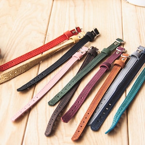 May include: Assortment of 12 leather camera straps in various colors, including red, pink, green, brown, blue, and teal. The straps are all made of leather and have a simple design.