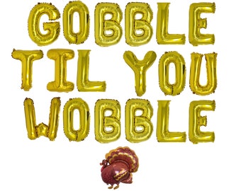 May include: A set of gold foil letter balloons spelling out the phrase GOBBLE TIL YOU WOBBLE, arranged in three rows. Below the text is a single foil balloon shaped like a turkey with brown, red, and gold feathers and a detailed pattern.