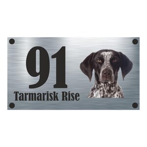 May include: A silver metal house number sign with the number 91 and the text "Tarmariks Rise" in black. A black and white dog's head is visible on the right side of the sign.