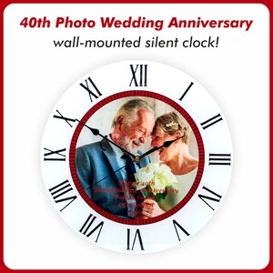 May include: White round wall clock with Roman numeral markings. The clock face features a red border and a photo of a couple celebrating their 40th wedding anniversary. The text "Happy 40th Ruby Wedding Anniversary Paul & Joanne 17th August 1983" is printed on the photo.