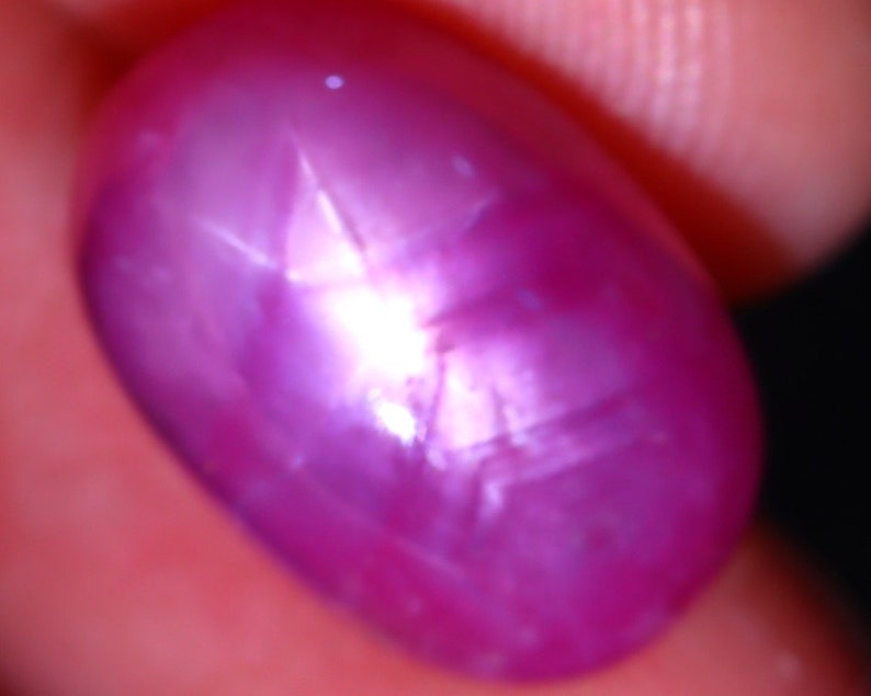 Peut inclure: Gros plan sur une pierre pr&eacute;cieuse de rubis &eacute;toil&eacute; rose. Le rubis est taill&eacute; en cabochon et pr&eacute;sente un motif en forme d'&eacute;toile.