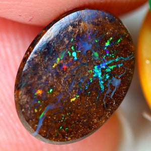 May include: A brown opal cabochon with a dark brown matrix and iridescent flashes of blue, green, and red.