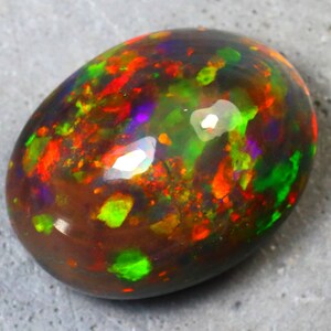 K&ouml;nnte beinhalten: Ein ovaler Opal-Edelstein in dunkelbraun mit Schimmern in Gr&uuml;n, Rot, Orange und Lila.
