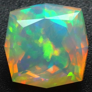 Op de afbeelding: Een levendige, veelkleurige opaal edelsteen met een gefacetteerde, kussen-vormige snede. De opaal vertoont een scala aan kleuren, waaronder groen, blauw, oranje en rood.