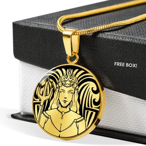 Könnte beinhalten: Goldkette mit einem runden Anhänger, der eine Schwarzweißillustration einer Frau mit Krone und Dreizack zeigt. Der Anhänger ist von einem Wellendesign umgeben.