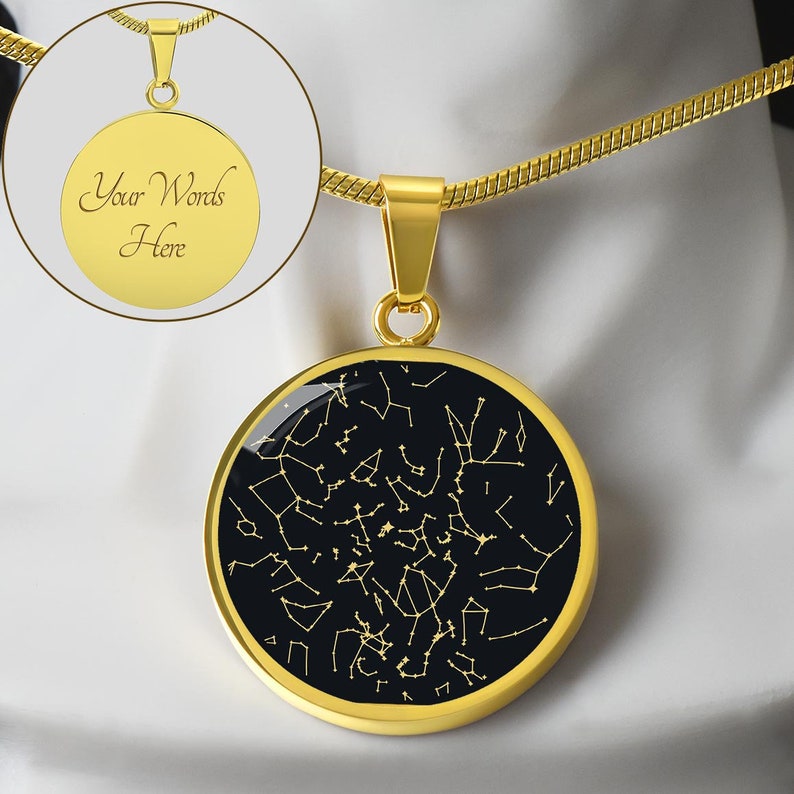 May include: Gold-colored pendant necklace featuring a round pendant with a black background and a constellation design in gold. The necklace includes a gold chain and a smaller inset image with the text "Your Words Here".