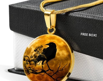 May include: A gold necklace with a round pendant featuring a black raven silhouette perched on a branch against a backdrop of a smoky, orange moon.