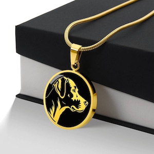 May include: A gold chain necklace with a round pendant featuring a black silhouette of a dog's head.