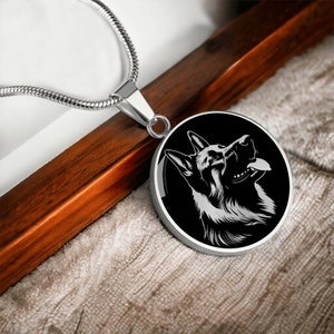 May include: A silver chain necklace with a round pendant featuring a black and white silhouette of a German Shepherd dog's head.