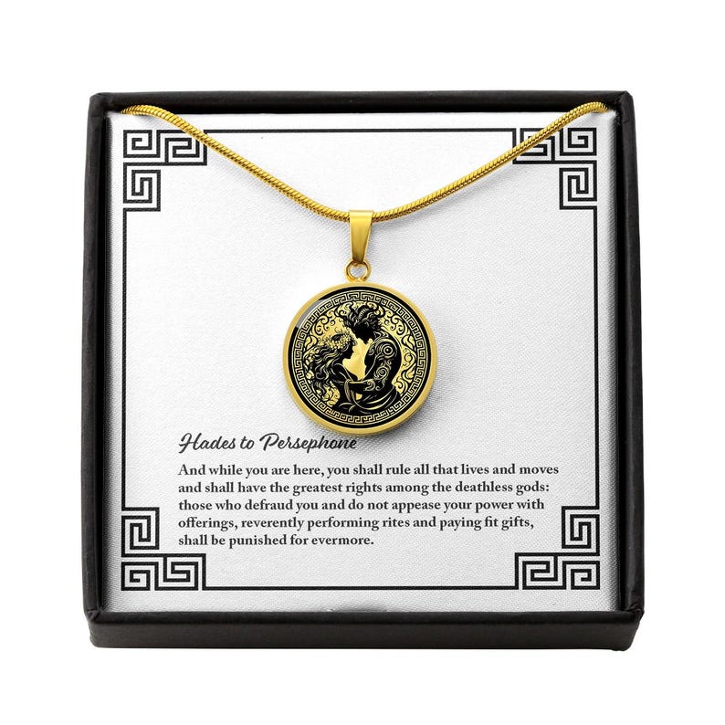 May include: A gold necklace with a round pendant featuring a black and gold illustration of Hades and Persephone. The pendant has a quote from Hades to Persephone: "And while you are here, you shall rule all that lives and moves and shall have the greatest rights among the deathless gods: those who defraud you and do not appease your power with offerings, reverently performing rites and paying fit gifts, shall be punished for evermore."