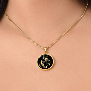 May include: A gold chain necklace with a round black pendant featuring a gold silhouette of a German Shepherd dog's head.