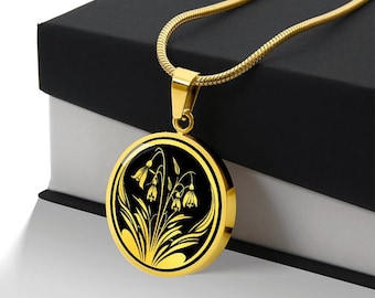 May include: A gold necklace with a round pendant featuring a black and gold design of stylized flowers. The pendant is on a black background.