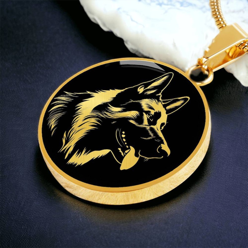 May include: A gold-toned necklace with a round pendant featuring a black silhouette of a German Shepherd dog. The pendant has a gold rim.