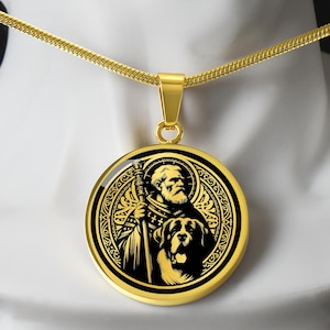 Op de afbeelding: Goudkleurige hangerketting met een gedetailleerde illustratie van een man met een staf en een hond. De hanger heeft een zwart-goud ontwerp in een cirkelvorm. De ketting is ook goudkleurig.