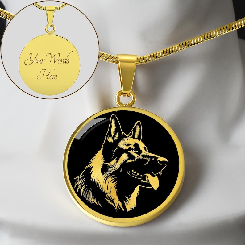 May include: Gold necklace with a round pendant featuring a black and gold silhouette of a German Shepherd dog's head. The pendant has a black background and a gold rim. The necklace is on a white surface.