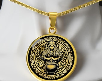 May include: Gold-toned pendant necklace featuring a round pendant with a black and gold design. The pendant depicts a woman with long hair over a cauldron, surrounded by Celtic knotwork. The necklace has a delicate chain.