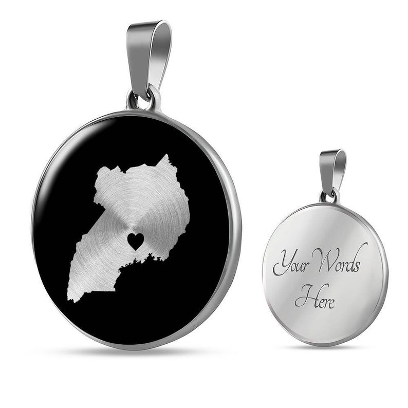 May include: A silver necklace with a round pendant featuring a black background and a silver outline of Uganda with a small heart in the center. The back of the pendant is silver and has the text "Your Words Here".