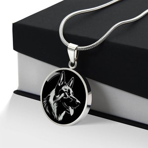 May include: A silver chain necklace with a round pendant featuring a black and white silhouette of a German Shepherd dog's head.