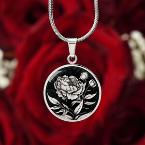 May include: A silver chain necklace with a black and white round pendant featuring a detailed illustration of a single peony flower.