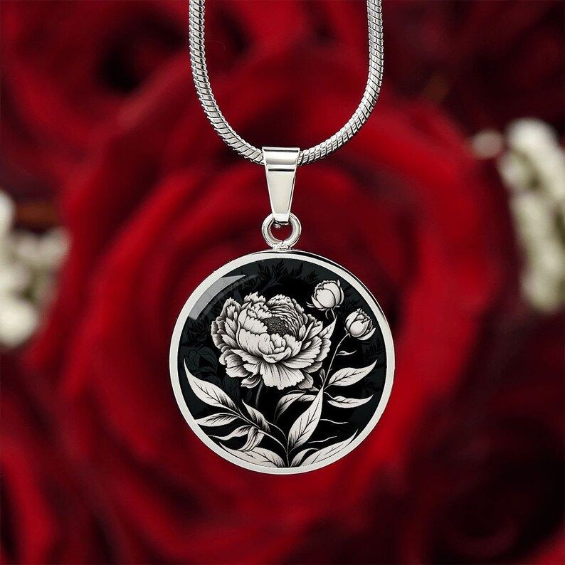 May include: A silver chain necklace with a black and white round pendant featuring a detailed illustration of a single peony flower.