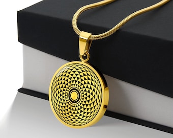 May include: A gold chain necklace with a round pendant featuring a black and gold geometric design. The pendant has a circular pattern of triangles and a small circle in the center.