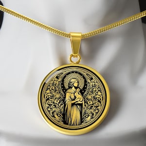 May include: A gold necklace with a round pendant featuring a black and gold image of a woman holding a rabbit. The woman is surrounded by intricate floral designs.