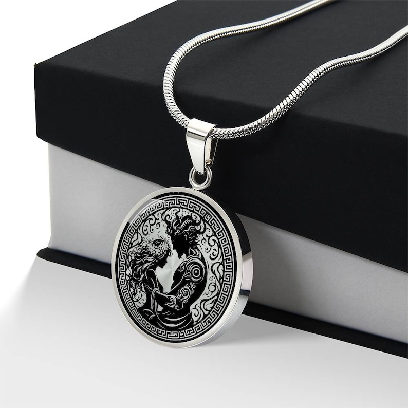 May include: A silver necklace with a round pendant featuring a black and white illustration of a couple embracing. The pendant is surrounded by a decorative border.