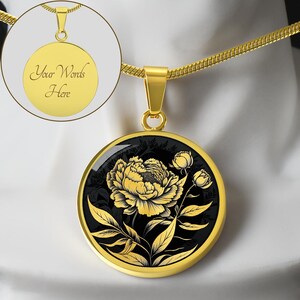 May include: Gold necklace with a round pendant featuring a black and gold floral design. The pendant has a black background with a gold peony flower and leaves.