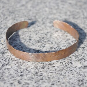 May include: A hammered copper bracelet with a rustic finish.
