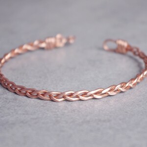 Peut inclure: Un bracelet jonc tressé en or rose. Le bracelet est fait d'un seul fil de métal tressé pour créer un design délicat et élégant.