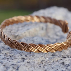 May include: A braided copper bracelet with a smooth, polished finish. The bracelet is made of multiple strands of copper wire that are woven together to create a unique and stylish design.