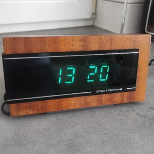 May include: A handmade wooden sign with the word "Welcome" in a whimsical font. The sign is painted white with a distressed finish, and features a floral design in pinks and greens. It measures approximately 30 cm wide.